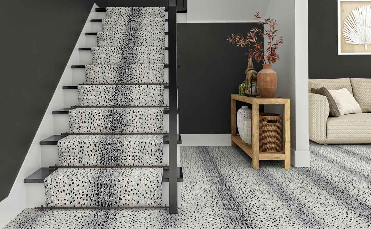 modern entryway with styled wood entry table, staircase and gray walls with gray animal print carpet